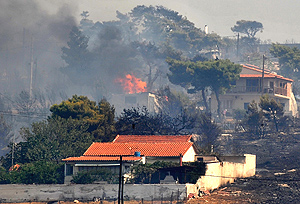 Dos casas 'asoman' entre la vegetación en llamas en los montes cercanos a Atenas | Afp